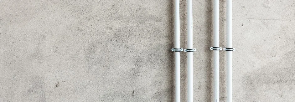 Drei weiße Rohre an Betonwand